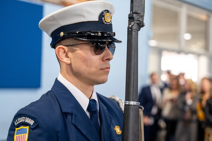 A photo of a member of the U.S. Coast Guard standing still with a ceremonial rifle.