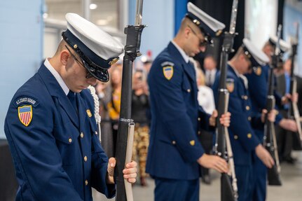 A photo of several members of the U.S. Coast Guard standing still with ceremonial rifles.