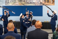 A photo of several members of the U.S. Coast Guard performing flips of ceremonial rifles.