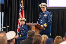 A photo of a man speaking on stage.