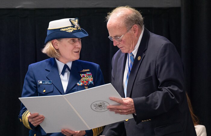 A photo of a man and woman looking at a ceremonial document.