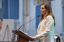 A photo of a woman speaking on stage.