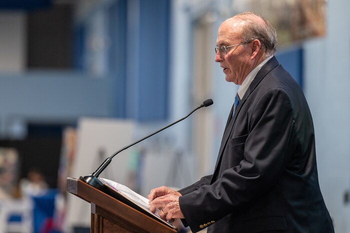 A photo of a man speaking on stage.