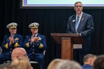 A photo of a man speaking on stage.