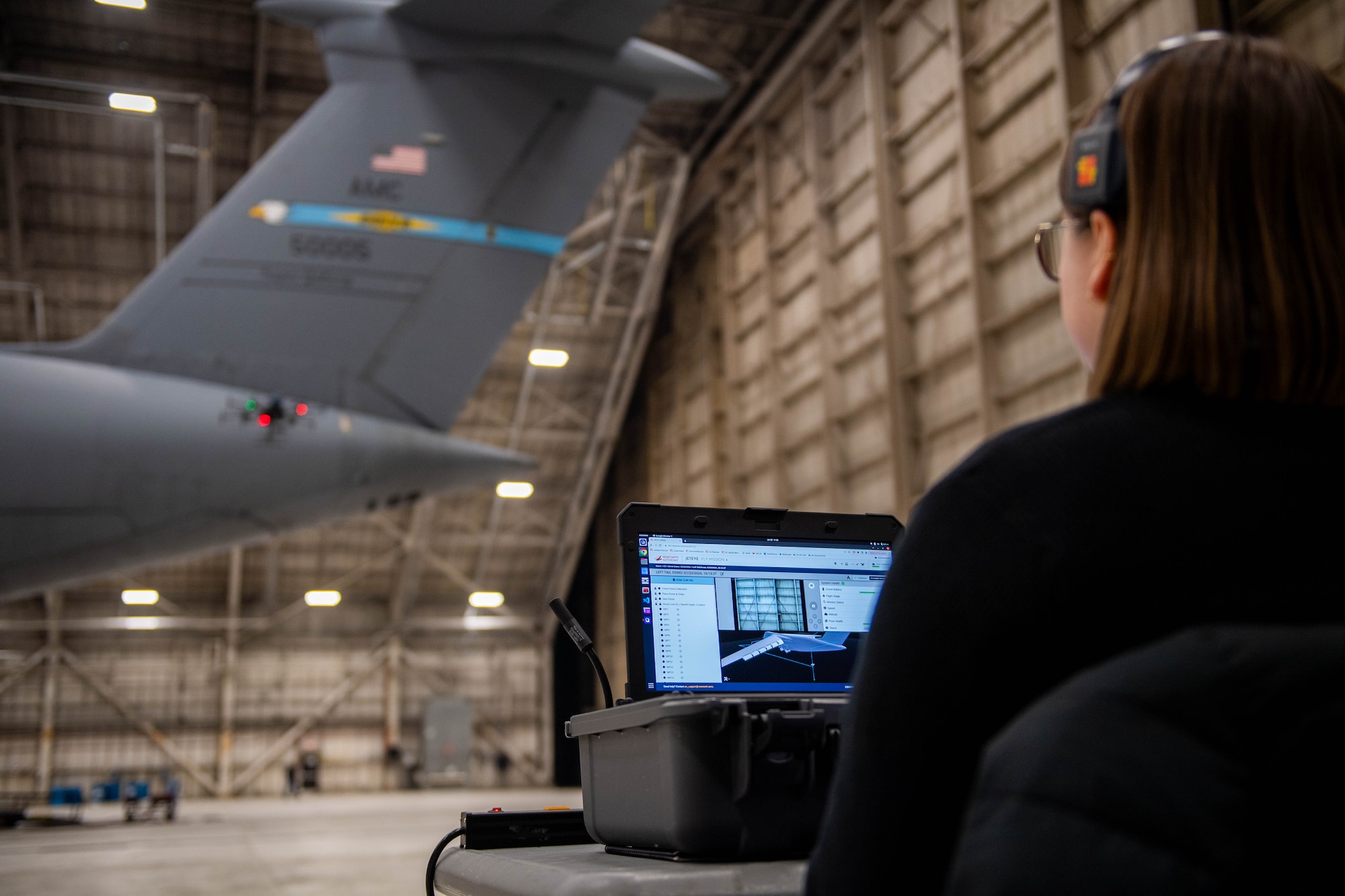 Sophie Legore, Near Earth Autonomy test engineer, evaluates drone footage as it scans a C-5M Super Galaxy at Dover Air Force Base, Delaware, January 23, 2024. Team Dover in cooperation with Boeing and Near Earth Autonomy tested a drone program for an autonomous C-5M Super Galaxy aircraft inspection project. Traditional inspections that require personnel to use a safety harness, maintenance stands, or vehicles can take hours to accomplish, but the drone can complete the same inspection in approximately 10 minutes. (U.S. Air Force photo by Tech. Sgt. J.D. Strong II)