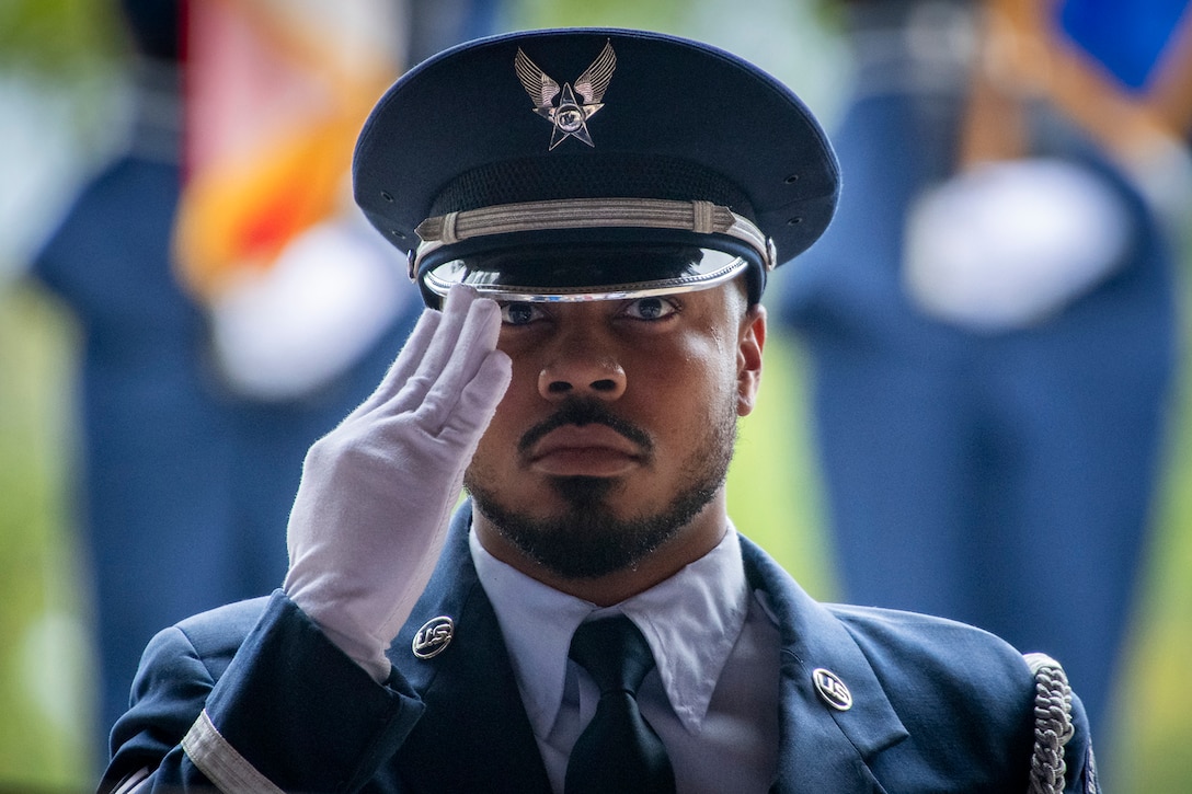 Close-up of an airman wearing white gloves saluting during a funeral demonstration.