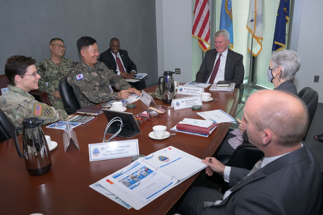 A group of people in uniforms and suits sit at a table talking.