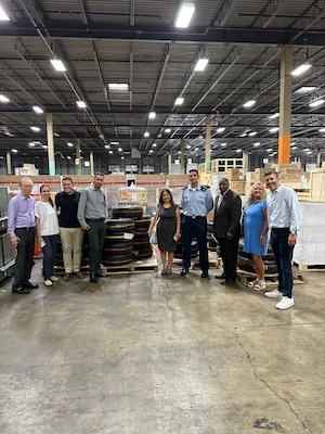 A group of men and women stand together in a warehouse.