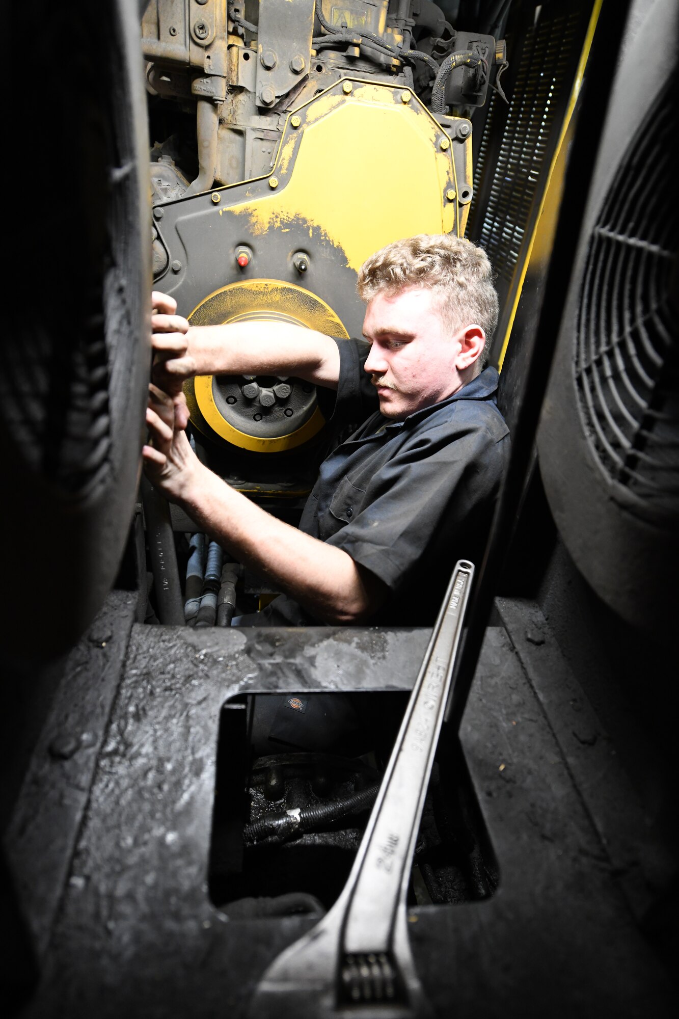 Mechanic fixes a hydraulic line inside a snowplow.