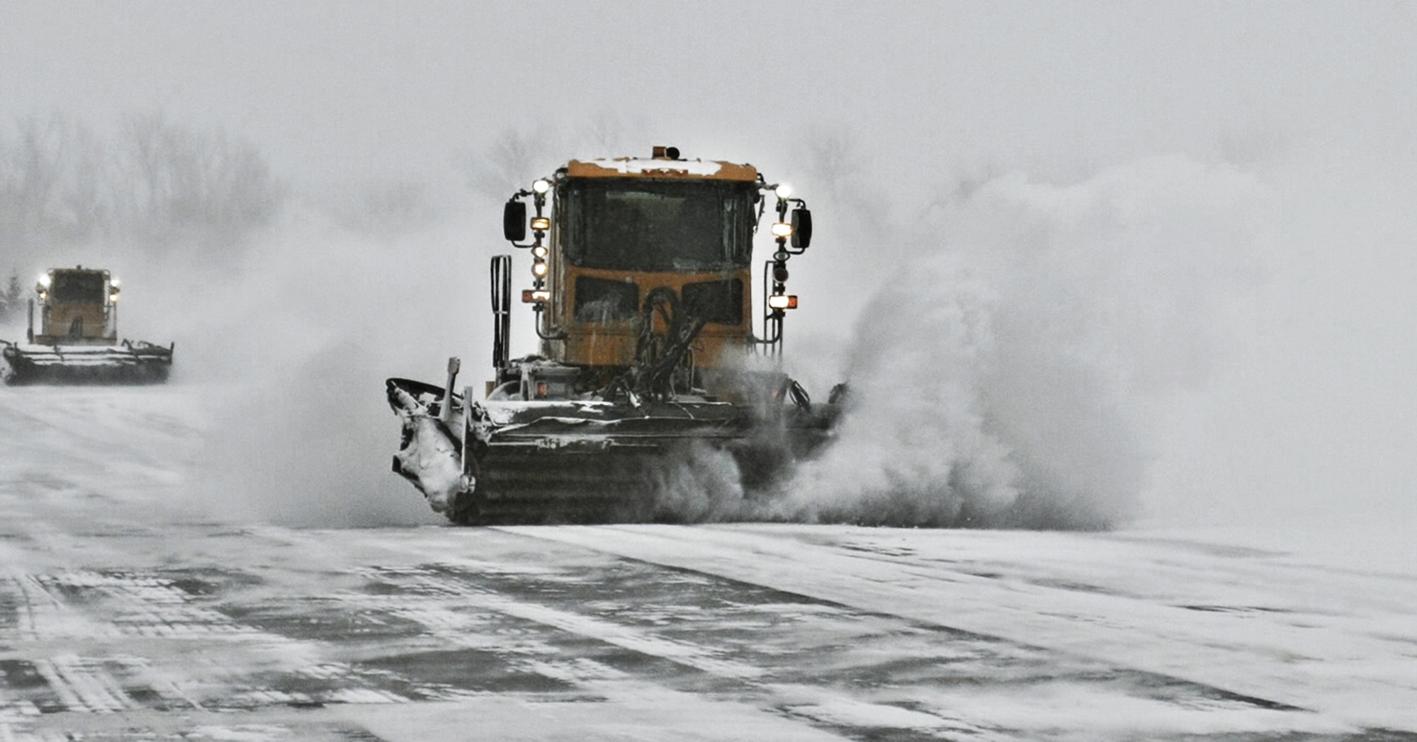 2 snowplows on runway throwing snow.