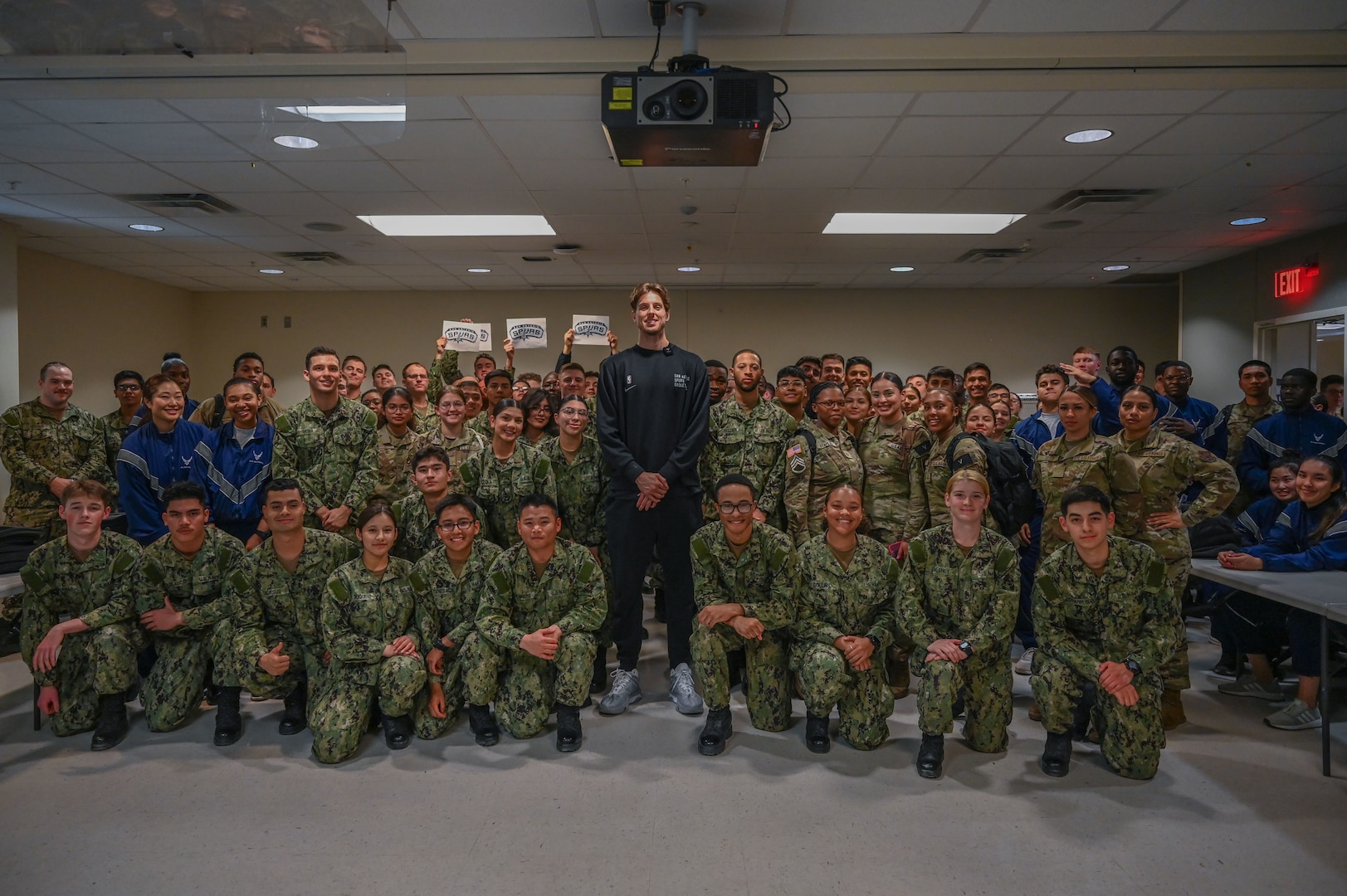 Zach Collins, San Antonio Spurs player, takes a group photo with Army, Navy and Air Force trainees during an autograph session while visiting the Medical Education and Training Campus on Joint Base San Antonio-Fort Sam Houston, TX, Jan. 25, 2024.