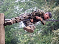 U.S. Marine with Marine Corps Embassy Security Group maneuvers over a bar on an obstacle course during a culminating event of a Marine Corps Martial Arts Program course on Marine Corps Base Quantico, VA., June 30, 2023. The culminating event included a 3-mile hike to the obstacle course, completing the obstacle course three times, a squad competition on the obstacle course, pugil stick combat, completing the endurance course, shallow water grappling, and a 3-mile hike back to the MSAU facility. (U.S. Marine Corps photo by Sgt. Ramon Garcia)