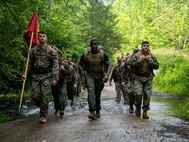 U.S. Marines with Marine Corps Embassy Security Group and Marine Security Guard Security Augmentation Unit hike during a culminating event of a Marine Corps Martial Arts Program course on Marine Corps Base Quantico, VA., June 30, 2023. The culminating event included a 3-mile hike to the obstacle course, completing the obstacle course three times, a squad competition on the obstacle course, pugil stick combat, completing the endurance course, shallow water grappling, and a 3-mile hike back to the MSAU facility. (U.S. Marine Corps photo by Sgt. Ramon Garcia)