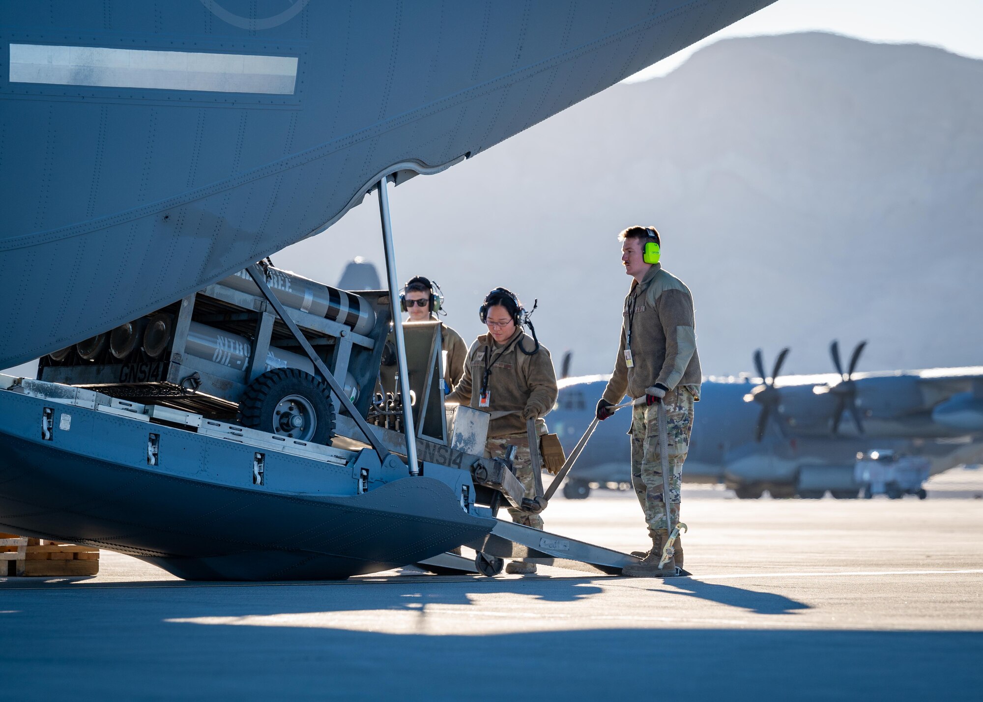 Airman work together to load cargo onto a C-130 Hercules.