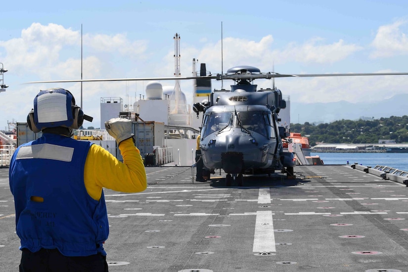 A sailor instructs a chopper on board a ship.