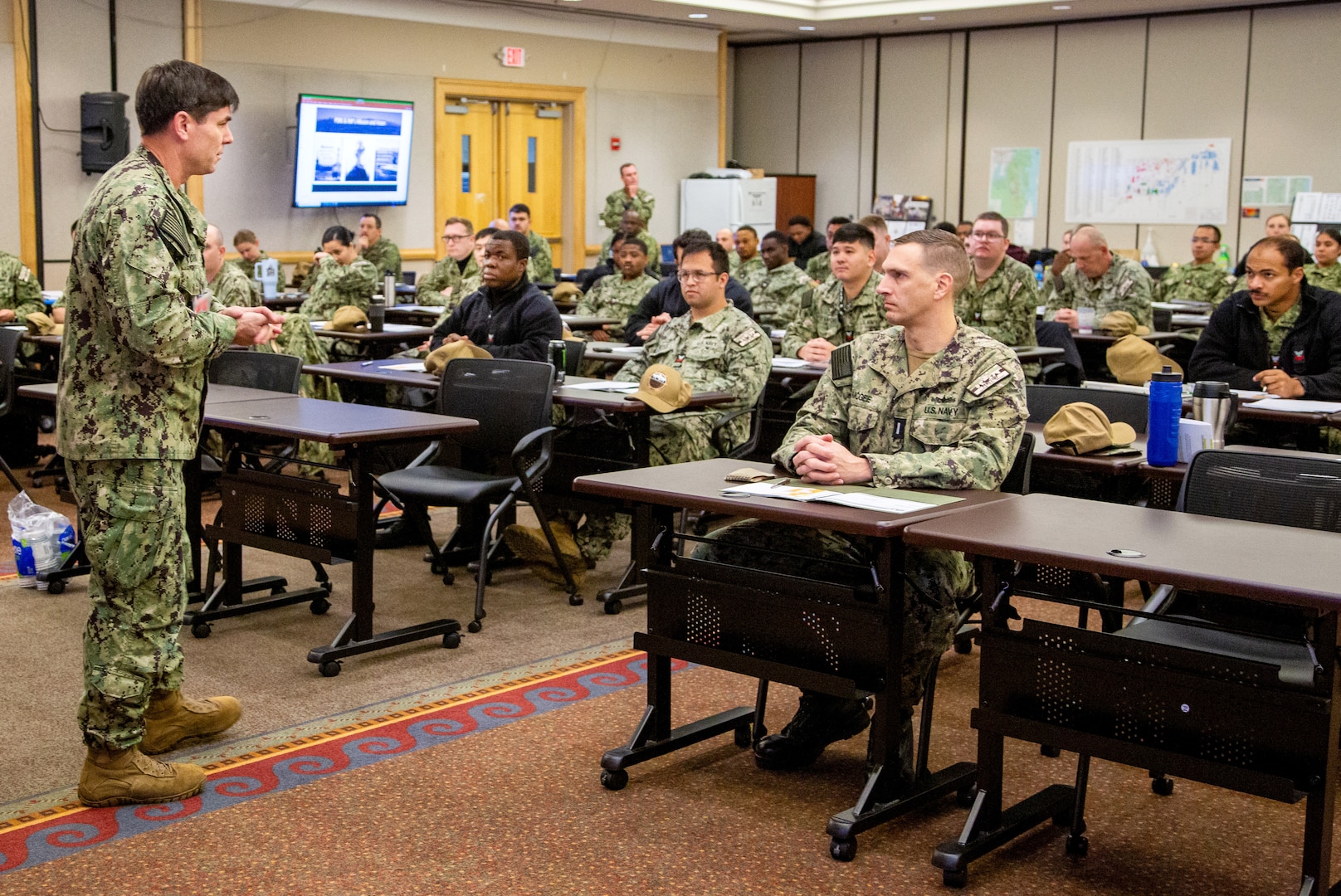 Capt. JD Crinklaw, commander, Puget Sound Naval Shipyard & Intermediate Maintenance Facility, speaks to SurgeMain Sailors Jan. 7, 2023, at Naval Base Kitsap’s Olympic Lodge Training Center, in Bremerton, Washington. His briefing helped kick off the start of "DEPLOYEX24," a two-week deployment exercise, utilizing over 110 Navy Reservist's for PSNS & IMF'S six areas of responsibility. (U.S Navy photo by Wendy Hallmark)