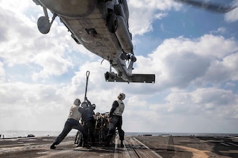 Sailors aboard USS Sterett (DDG 104) attach a cargo pallet to an MH-60S Sea Hawk helicopter during a replenishment-at-sea.