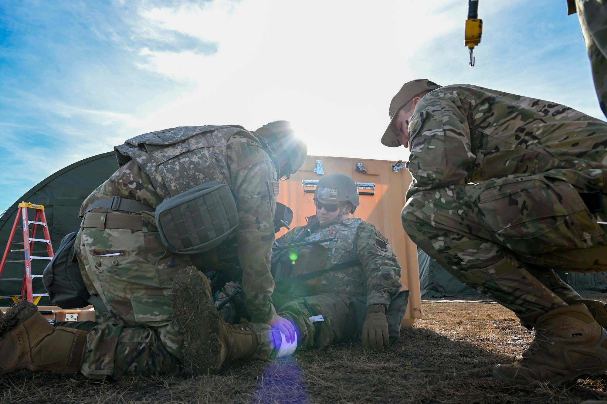 An Airman sitting on the floor with a bandage and surrounded by others