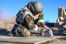 An Airman saws  piece of wood