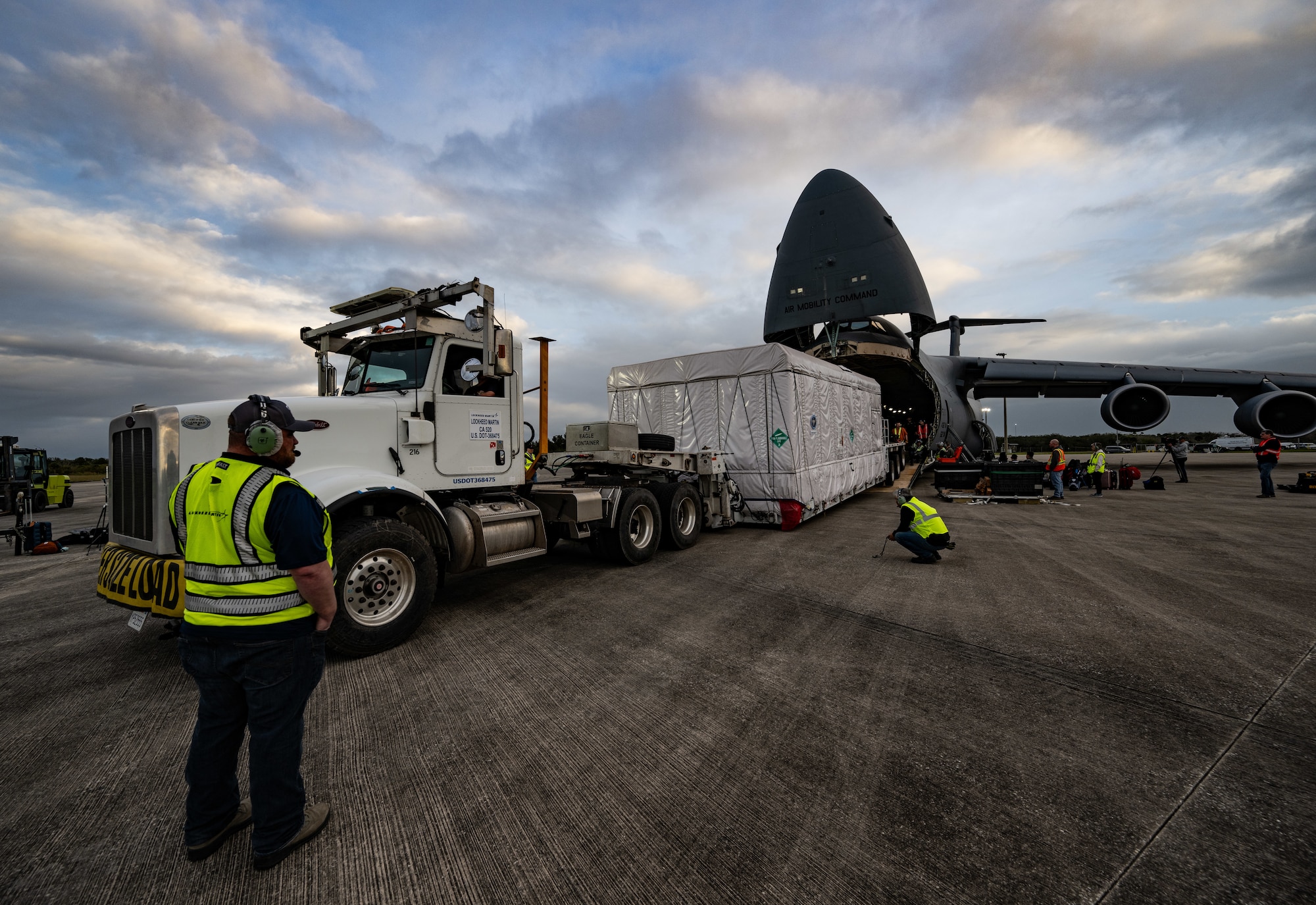 Lockheed Martin crew members monitor vehicle clearance during a National Oceanic and Atmospheric Administration Geostationary Operational Environmental Satellite offload from a U.S. Air Force C-5M Super Galaxy at NASA Kennedy Space Center on Merritt Island, Florida, Jan. 23, 2024. The 9th AS aircrew transported NOAA’s newest weather satellite, GOES-U, to Kennedy Space Center from Buckley Space Force Base, Colorado, using its oversized carrying capacity as the largest mobility aircraft in the Air Force’s inventory. GOES-U will be able to monitor severe weather, identify volcanic eruptions, measure land and sea surface temperatures, provide early alerts to emergency responders during wildfires and observe solar flares that could impact telecommunication on and around Earth. (U.S. Air Force photo by Staff Sgt. Marco A. Gomez)
