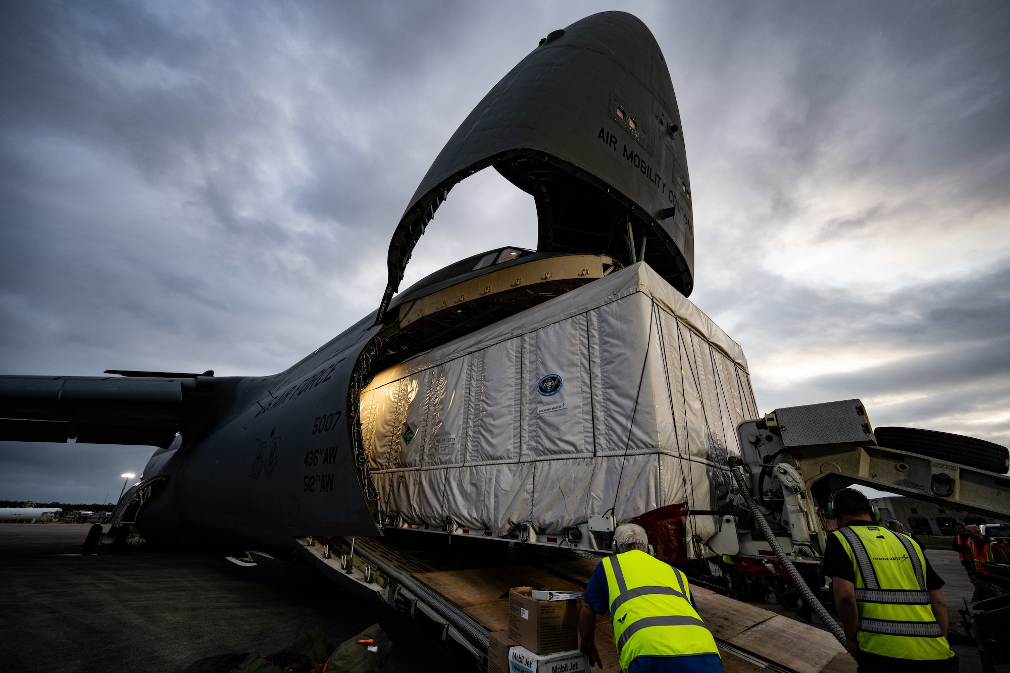 Lockheed Martin crew members monitor vehicle clearance while offloading a National Oceanic and Atmospheric Administration Geostationary Operational Environmental Satellite from a U.S. Air Force C-5M Super Galaxy at NASA Kennedy Space Center on Merritt Island, Florida, Jan. 23, 2024. The 9th AS aircrew transported NOAA’s newest weather satellite, GOES-U, to Kennedy Space Center from Buckley Space Force Base, Colorado, using its oversized carrying capacity as the largest mobility aircraft in the Air Force’s inventory. (U.S. Air Force photo by Staff Sgt. Marco A. Gomez)