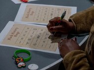 A member of Team Minot participates in a game of Black History Month (BHM) themed bingo at Minot Air Force Base, North Dakota, Feb. 1, 2024. After the opening remarks members of Team Minot participated in BHM bingo and trivia games. (U.S. Air Force Photo by Airman 1st Class Luis Gomez)