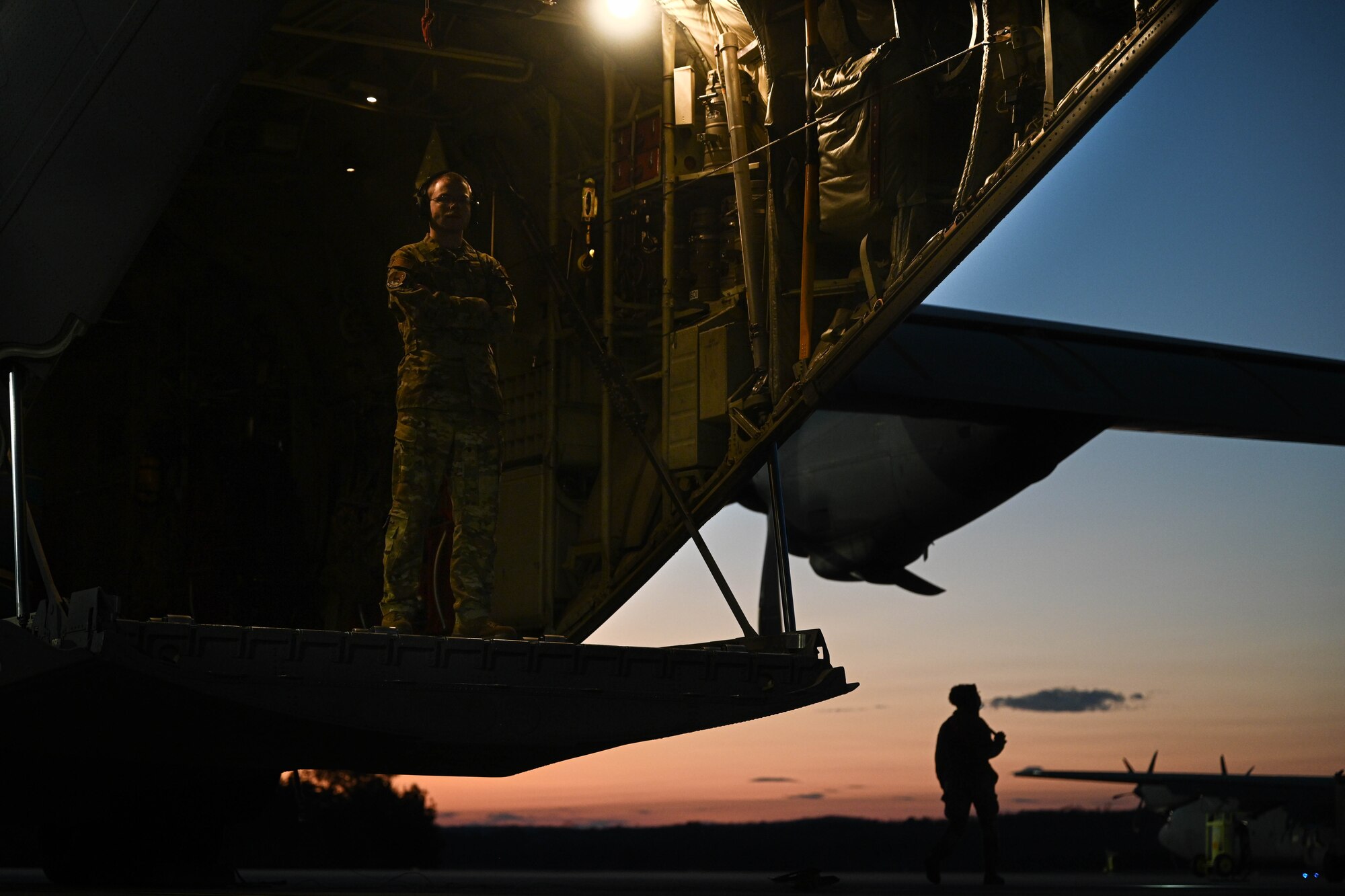 A loadmaster stands on a C-130 ramp.