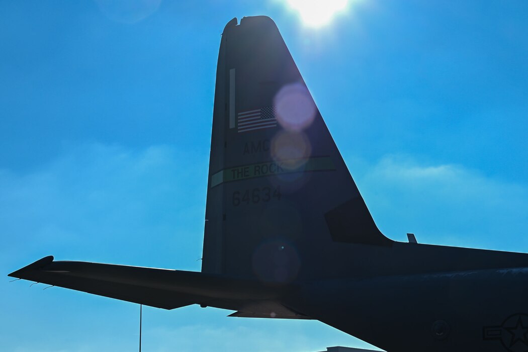 The sun shines bright behind the tail of an aircraft.