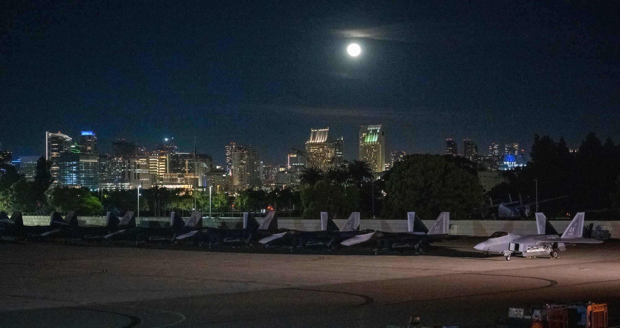 F-22 Raptors deployed under the 525th Expeditionary Fighter Squadron, 3rd Air Expeditionary Wing, Joint Base Elmendorf-Richardson, Alaska, sit on the airfield in front of a San Diego skyline during Exercise Bamboo Eagle 24-1 at Naval Air Station North Island, California, Jan. 26, 2024.
