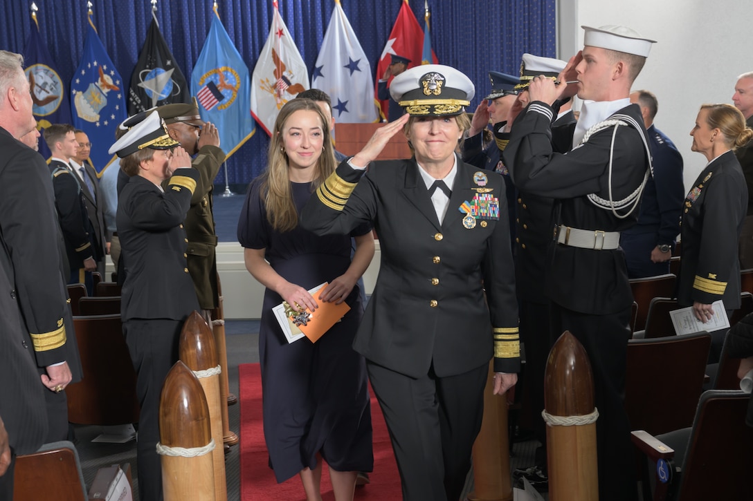VADM Michelle Skubic salutes the side boys flanking her path as she leaves an auditorium
