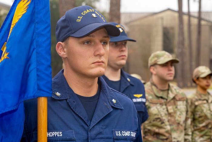 Coast Guard Petty Officer 3rd Class Nathaniel Hoppes, Coast Guard Cutter Axe machinery technician, stands at attention for the raising of the flag at Airman Leadership School on Keesler Air Force Base, Mississippi, Jan. 24, 2024.