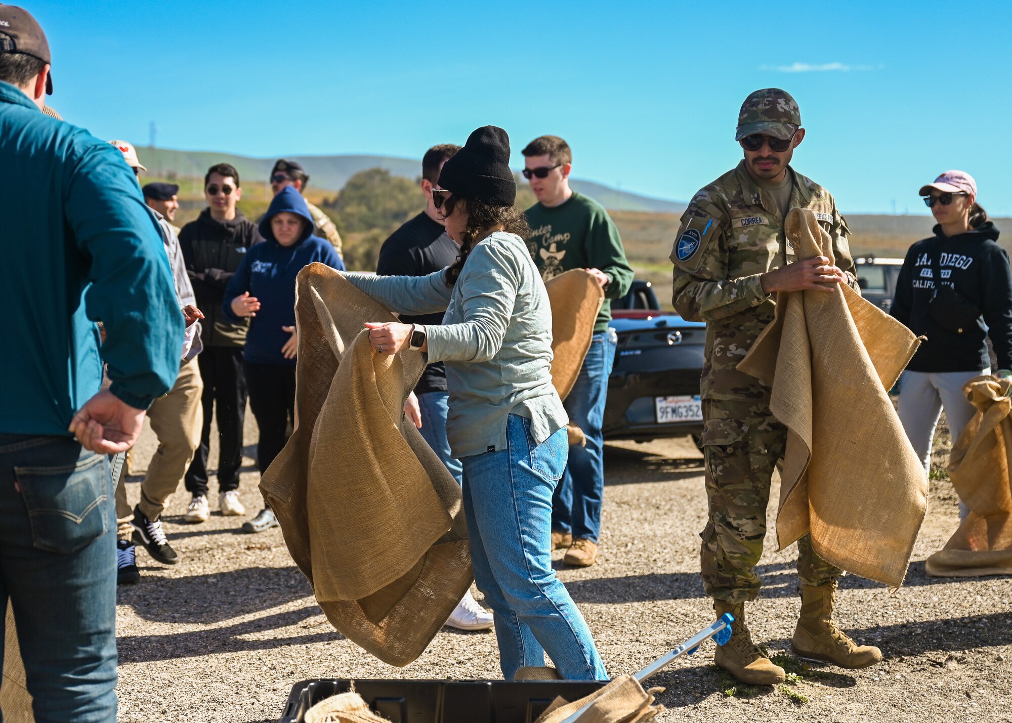 A Vandenberg Space Force Base volunteer distributes burlap bags to United States Space Force Guardians and U.S. Air Force Airmen during a Minuteman Beach cleanup day at Vandenberg Space Force Base.