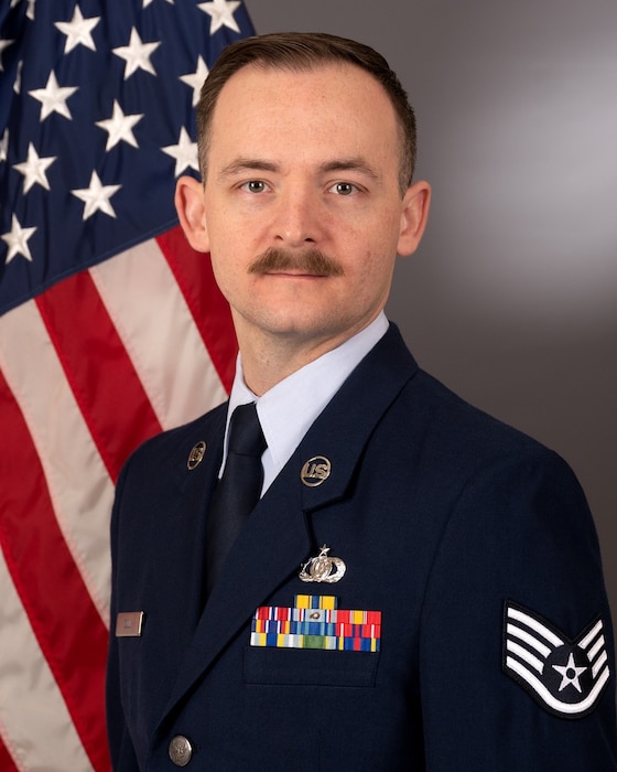 Official bio photo of Staff Sergeant Levi Cull in front of the American flag. He is wearing the blue service dress uniform.