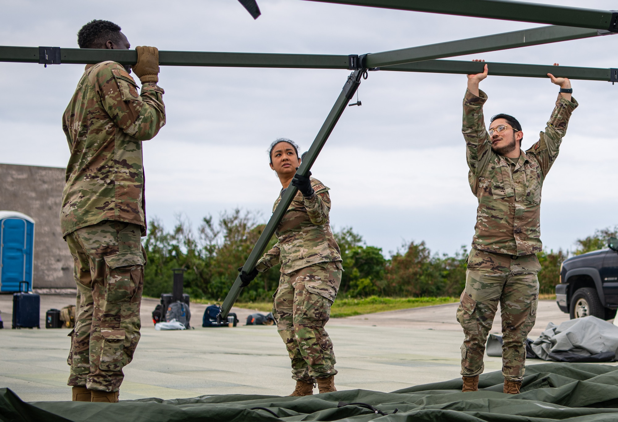 Three Airmen pitch a tent.