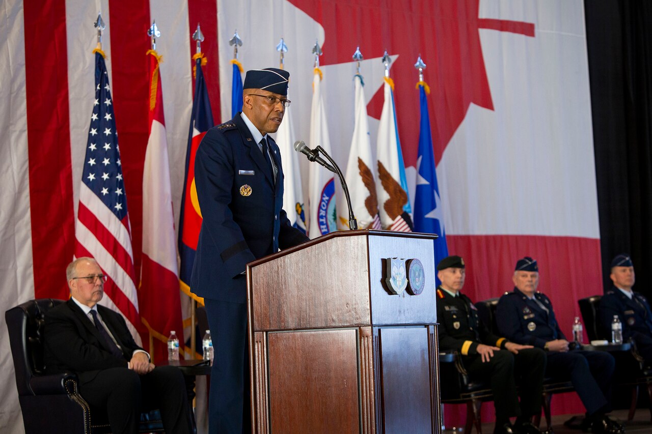 A military officer speaks from behind a podium.
