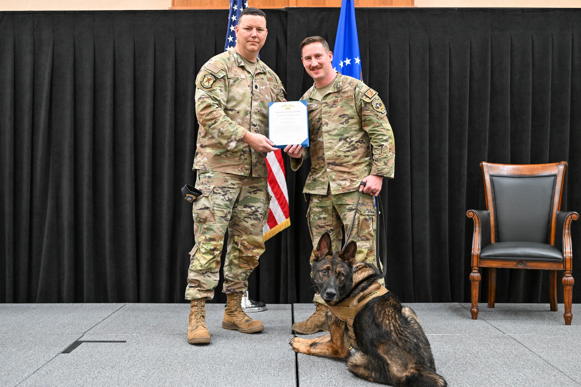 Two men in uniform stand with a dog