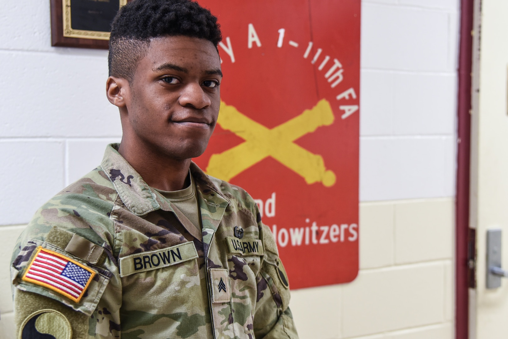 A Soldier poses in front of a field artillery sign.