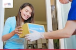 A delivery person hands a package to a woman