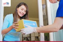 A delivery person hands a package to a woman