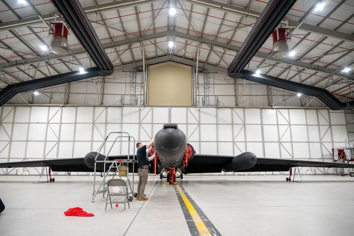 Airmen from the 99th Expeditionary Reconnaissance Squadron set masking tape on a U-2 Dragon Lady in preparation for a memorial drawing.