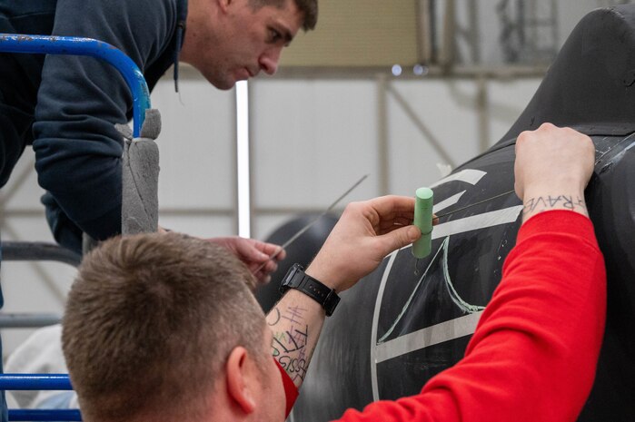 Members of the 99th Expeditionary Reconnaissance Squadron participate in a memorial drawing on a U-2 Dragon Lady.