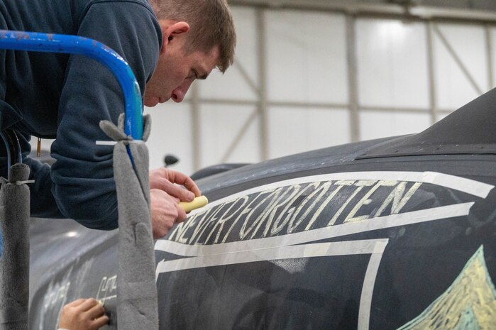 An Airman from the 99th Expeditionary Reconnaissance Squadron writes “NEVER FORGOTTEN” as part of a memorial drawing on a U-2 Dragon Lady.