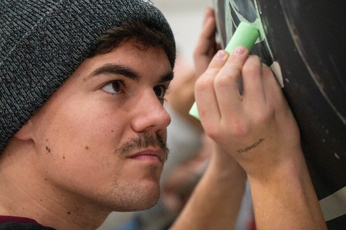 An Airman from the 99th Expeditionary Reconnaissance Squadron adds to a memorial drawing on a U-2 Dragon Lady.