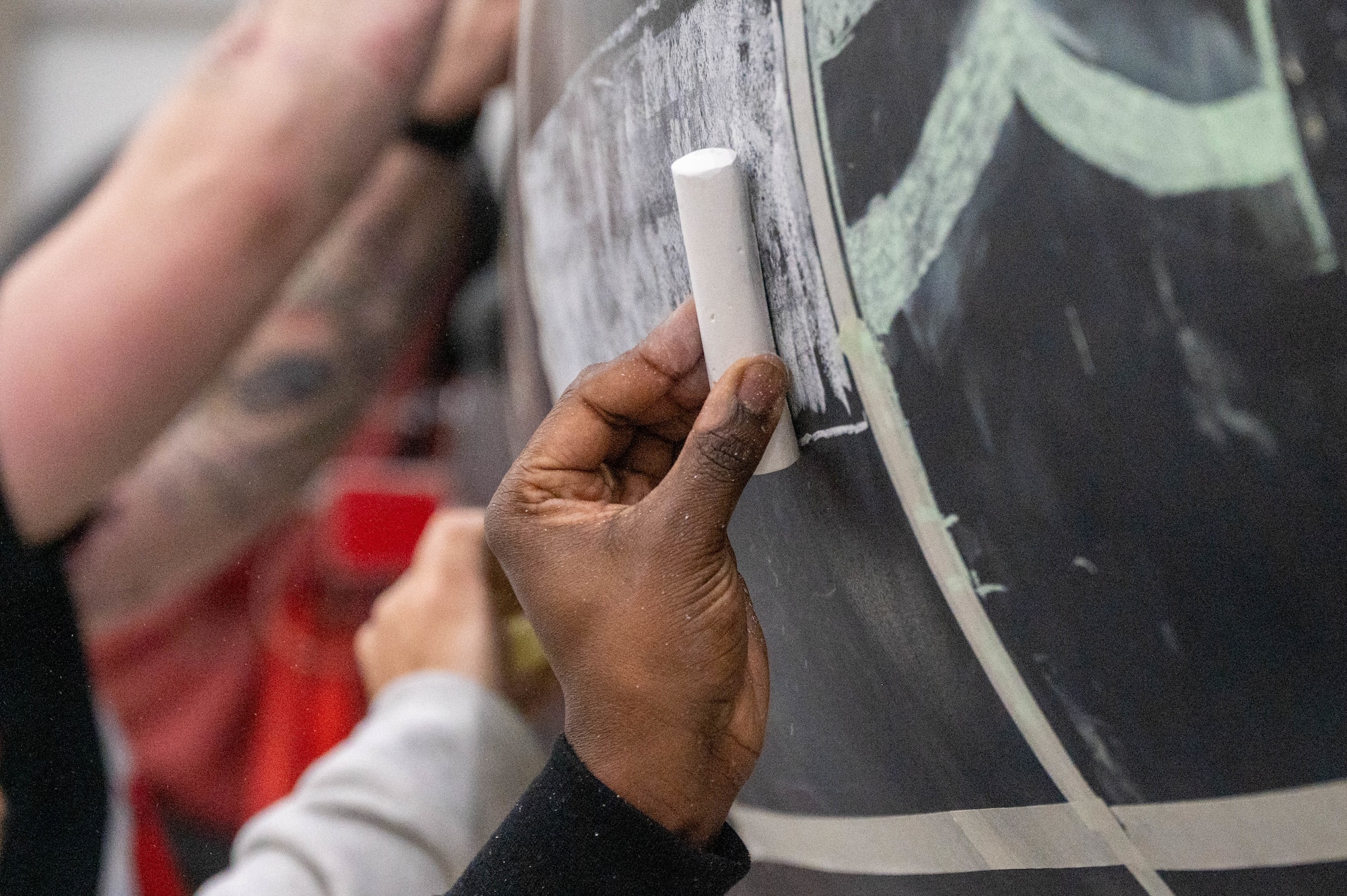 An Airman from the 99th Expeditionary Reconnaissance Squadron sketches out the Georgia state flag as part of a memorial drawing on a U-2 Dragon Lady.