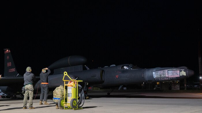 Members of the 99th Expeditionary Reconnaissance Squadron stand by while a U-2 Dragon Lady prepares to taxi.