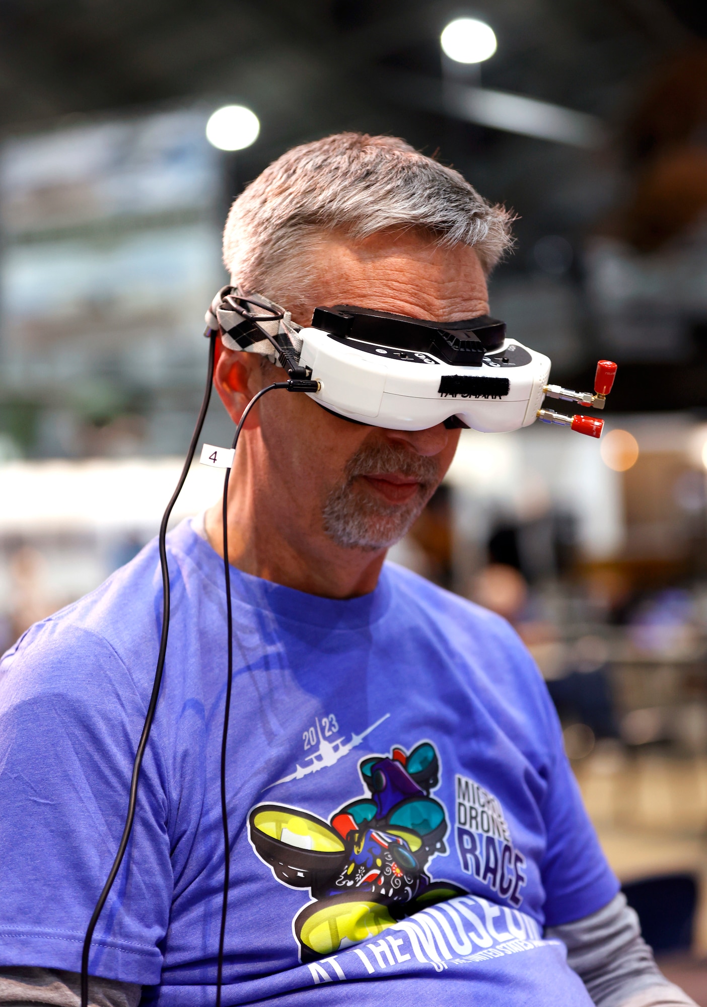 Image of a man in a purple t-shirt with short grey hair wearing a drone headset.