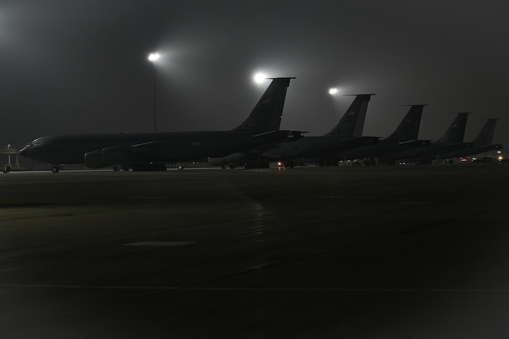Five aircraft parked in a row, in the dark.