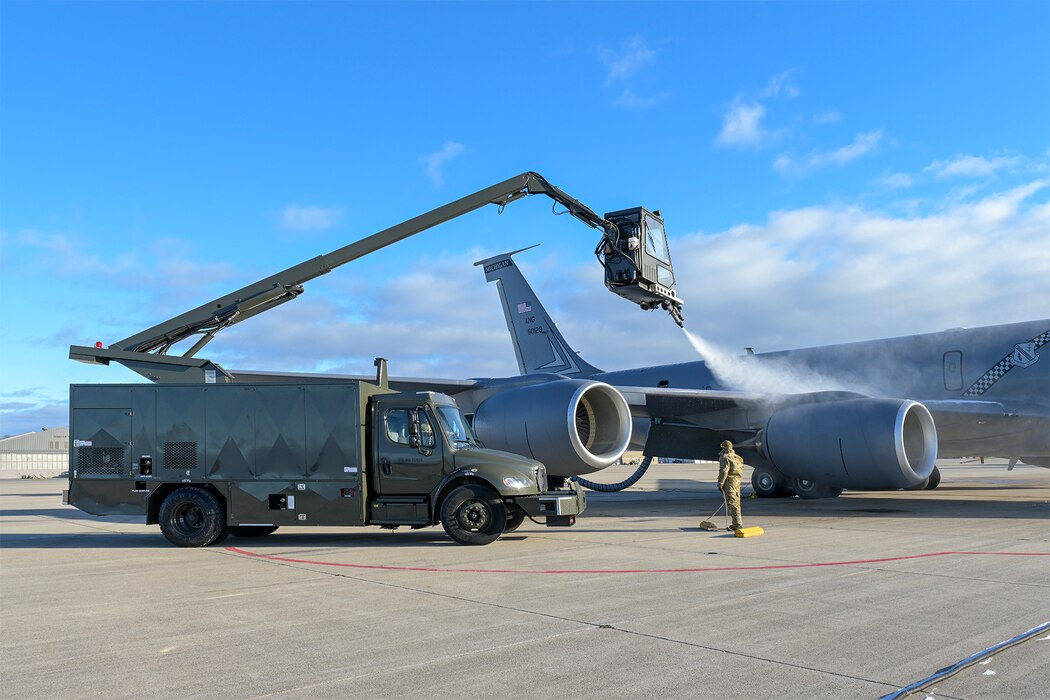 Deicing truck spraying wings of KC-135 Stratotanker aircraft.
