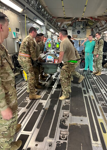 Medics from the 59th Medical Wing’s and Brooke Army Medical Center's Extracorporeal Membrane Oxygenation and Critical Care Air Transport Teams lift one of two patients in a C-17 Globemaster III to transport them to Brooke Army Medical Center, Joint Base San Antonio-Fort Sam Houston, Texas, Oct. 24, 2023. This is the first air transport of dual-patients on ECMO simultaneously in the Department of Defense’s history. (Courtesy photo by the medical team)