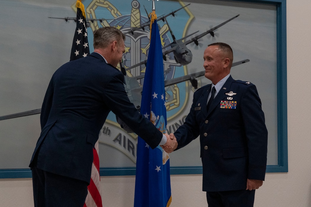 Two California Air National Guard officers shaking hands in front of Air Force Flag.